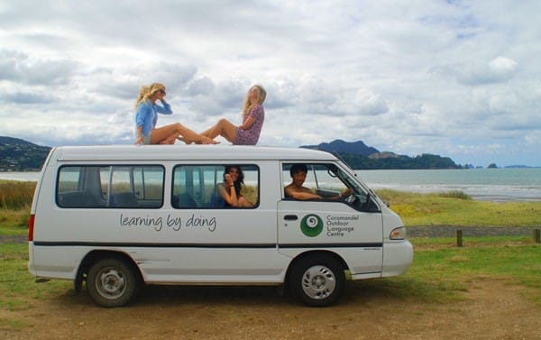Registro rego coche australia cuatro personas en una VAN y detrás la naturaleza y la playa